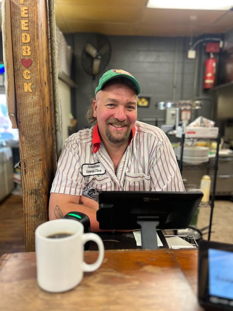 Kevin with a coffee at the register waiting to take your order